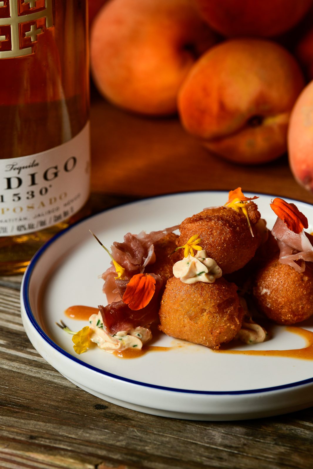 Golden arancini finished with edible flowers and prosciutto — PeachFest 2026